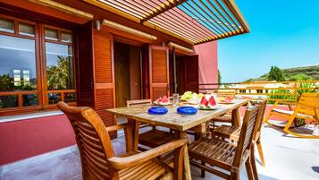 A wooden table with chairs, a wooden pergola, and a view of the landscape.