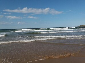A beach with waves and a clear sky.