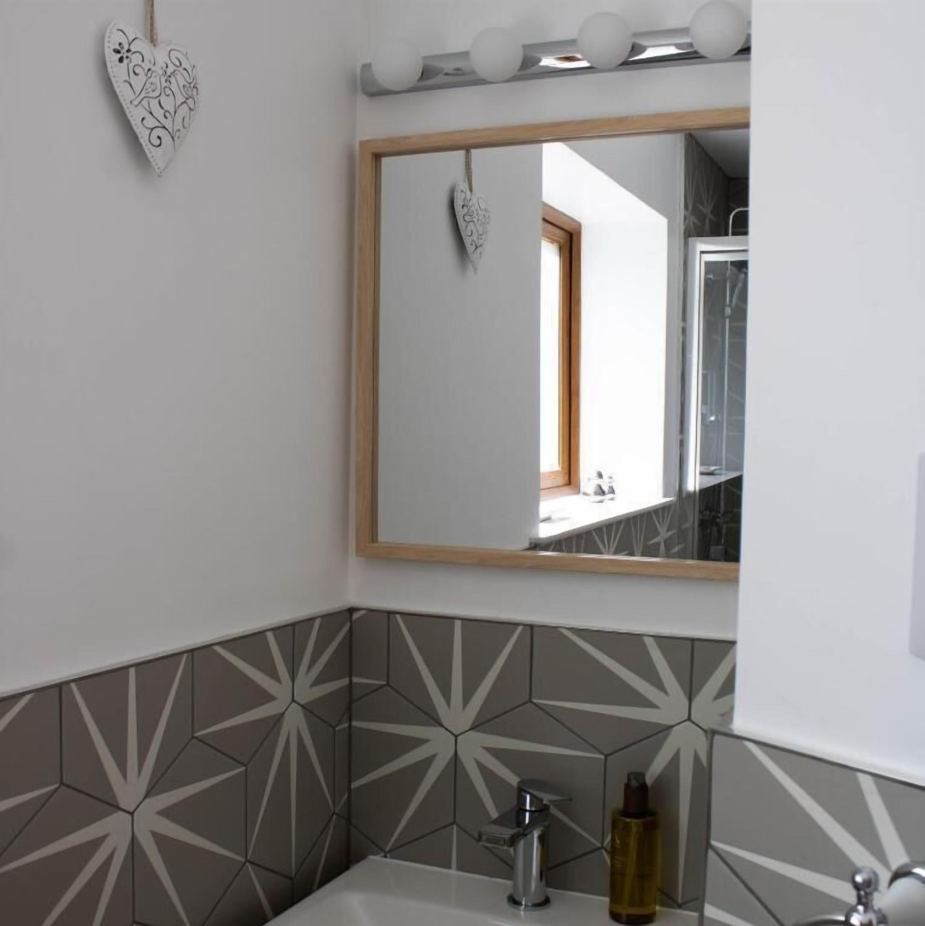 Ein Badezimmer mit Spiegel, einer herzförmigen Dekoration und einer backsplash aus geometrischen Fliesen.