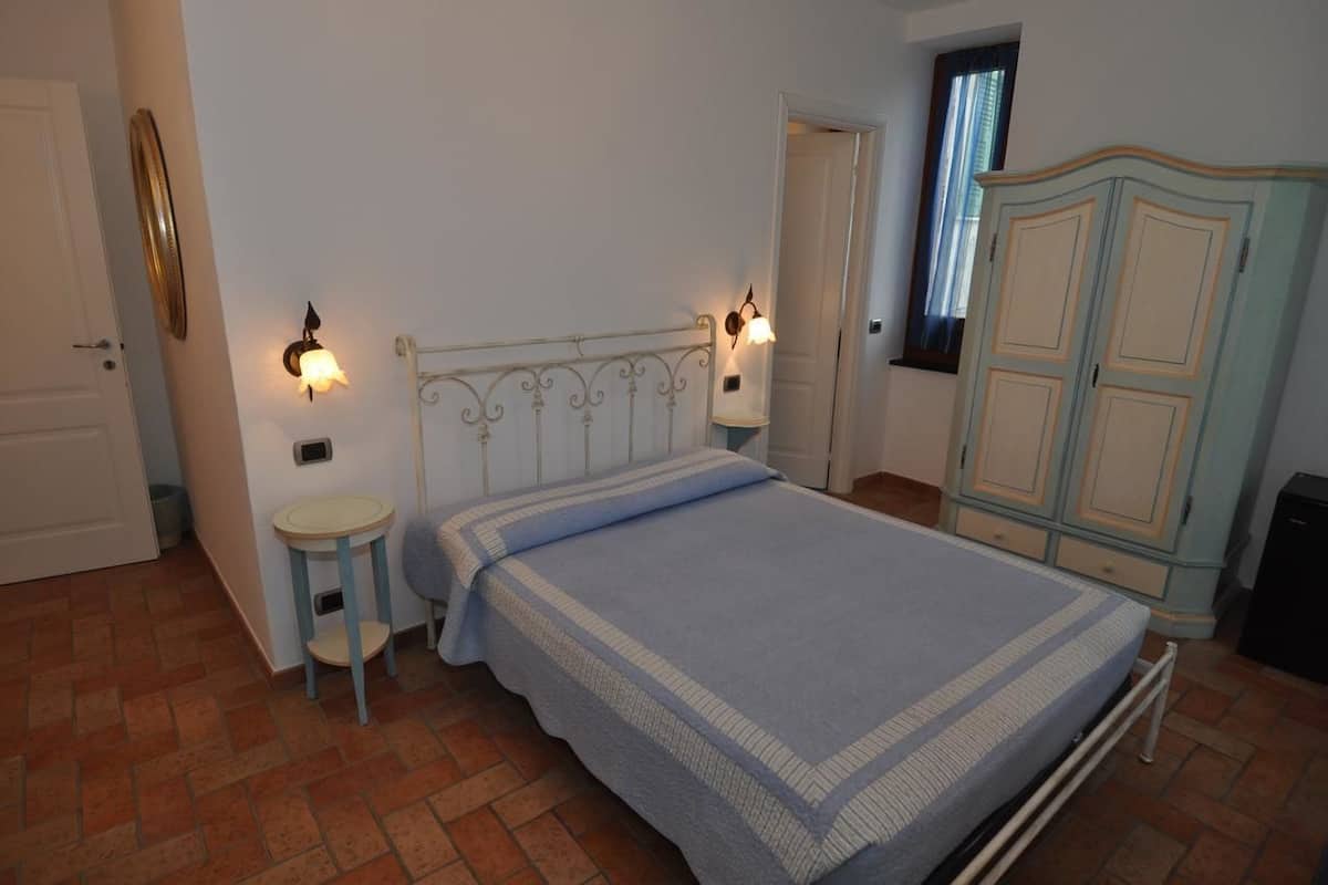 A bedroom with a bed, bedside tables, a wardrobe, and a door.