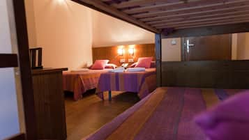 Habitación con dos camas, cabeceros de madera, una mesita de noche y una lámpara de pared.