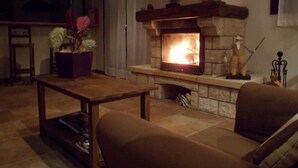 Una sala de estar acogedora con chimenea de piedra, una mesa de centro de madera y un sofá cómodo.