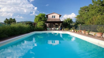 Een seizoensgebonden buitenzwembad, ligstoelen bij het zwembad