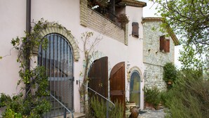 A building with arched doors, a stone wall, and a staircase leading to a balcony. - B&B With Pool and View of Assisi (Assisi)