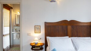 A bedroom with a wooden headboard, a bedside table with a lamp, a framed picture on the wall, and a window with curtains. - B&B With Pool and View of Assisi (Assisi)