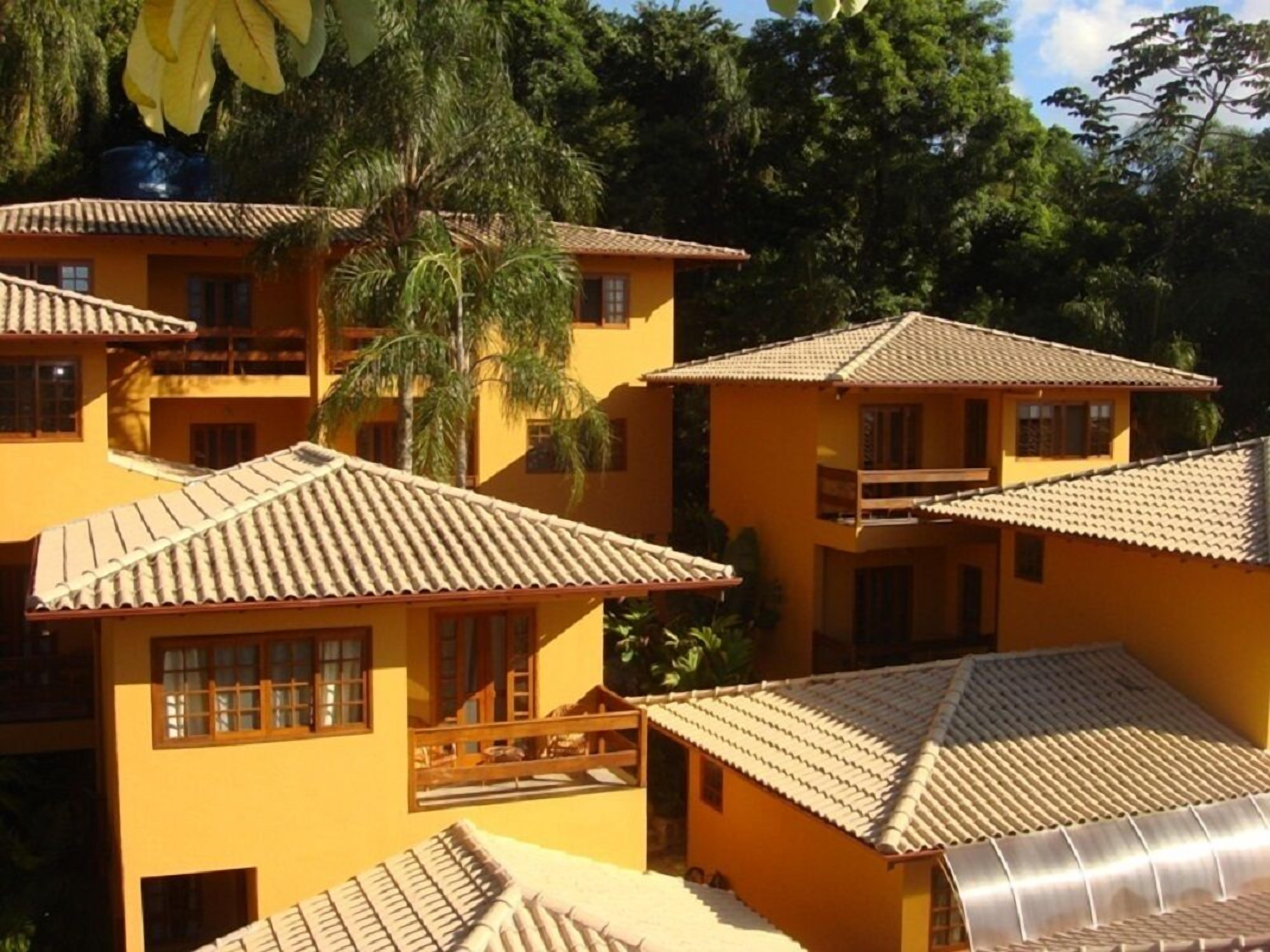 Um conjunto de edifícios amarelos com telhados de azulejo, rodeados por vegetação exuberante.