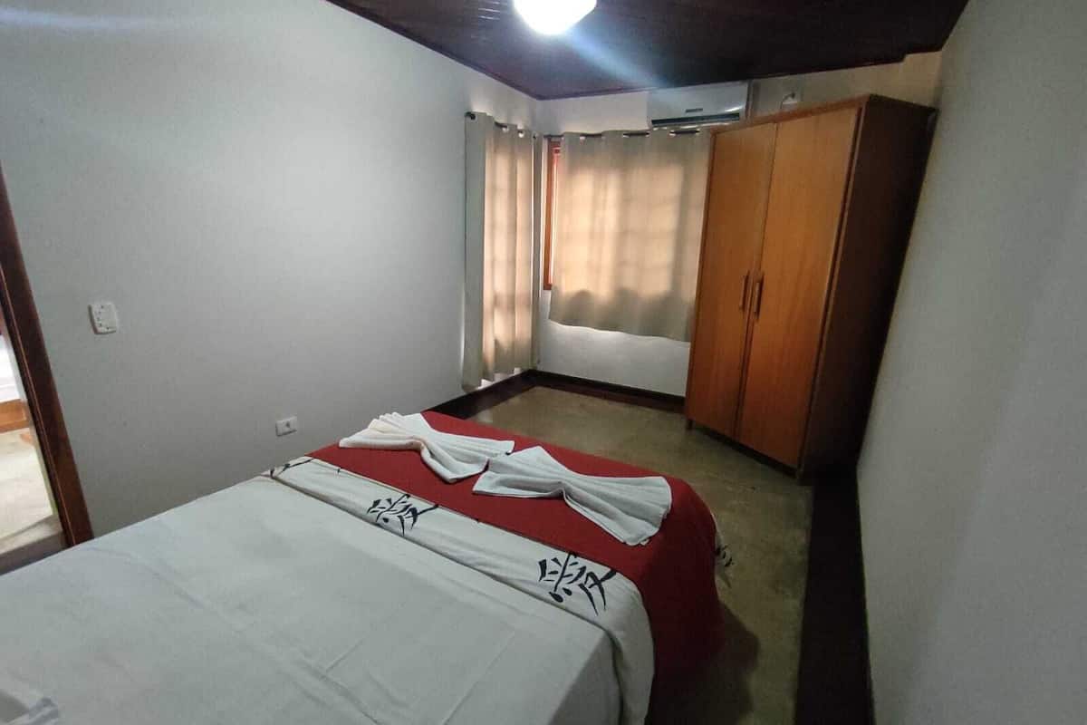 Une chambre à coucher avec un lit, une armoire et une fenêtre avec des rideaux.