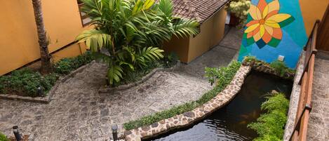 A courtyard with a stone pathway, a small water feature, and a colorful mural on a building.