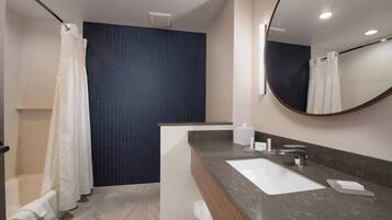 A modern bathroom with a large mirror, a white sink, and a shower area.