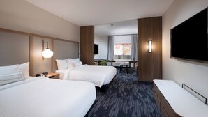 Habitación de hotel con dos camas, un escritorio, un televisor y una ventana con cortinas.