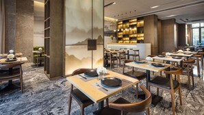 Un restaurant doté de nombreuses tables et chaises, d’un bar et d’une grande fresque murale.