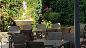 An outdoor patio with wicker furniture and a stone planter with flowers.