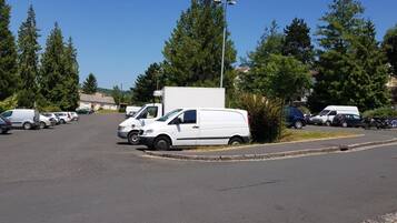 A parking lot with several white vans and cars parked.