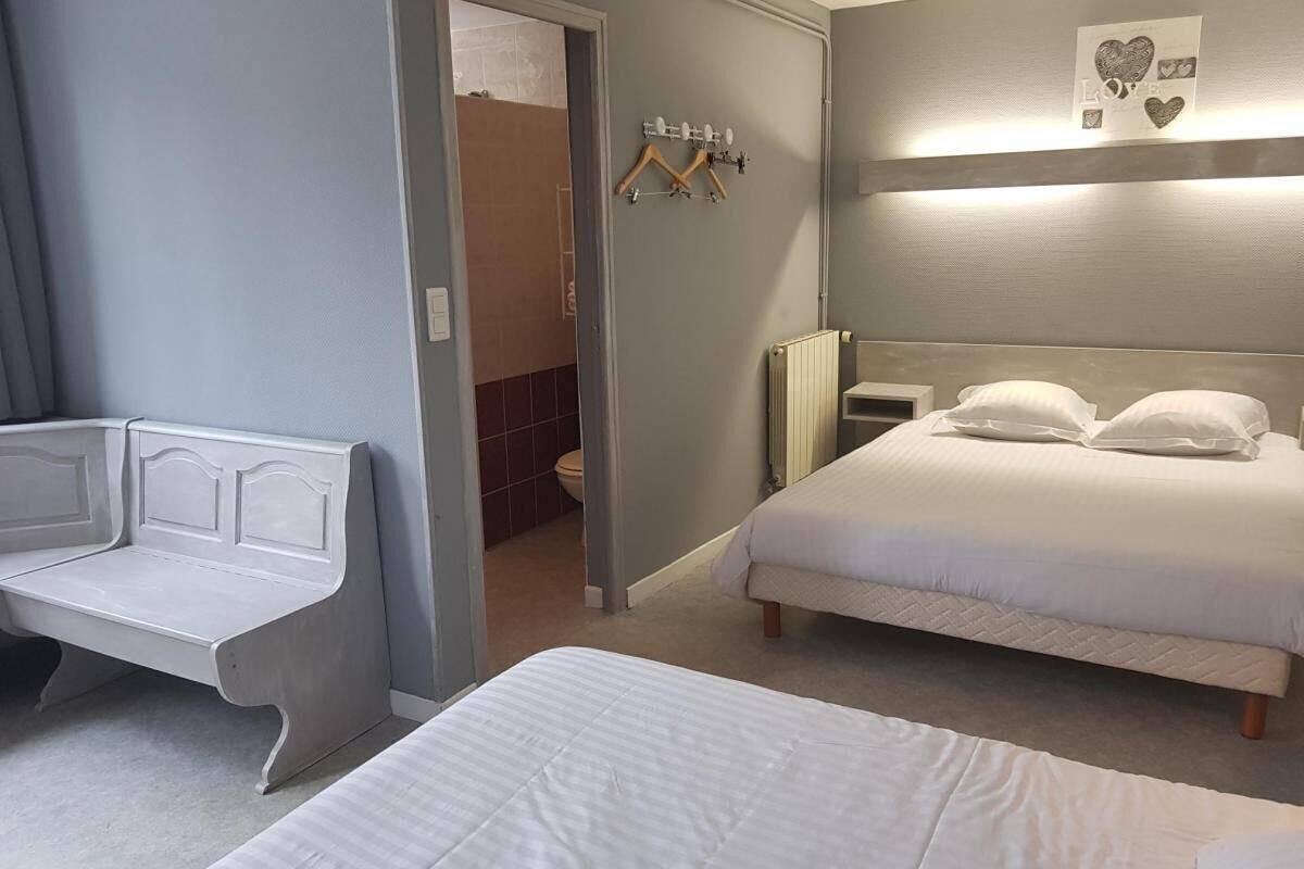 A hotel room with a bed, a bench, a radiator, and a wall-mounted light fixture.