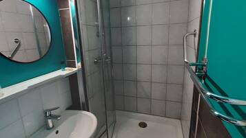 Een badkamer met een glazen douchecabine, een wastafel en een spiegel.