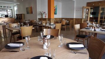 En restaurang med runda bord, dukade för middag, med svarta tallrikar, vita servetter och klara glas.