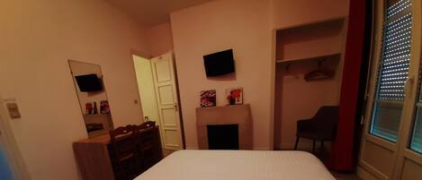 Un dormitorio con cama, cómoda, silla, televisor y chimenea.