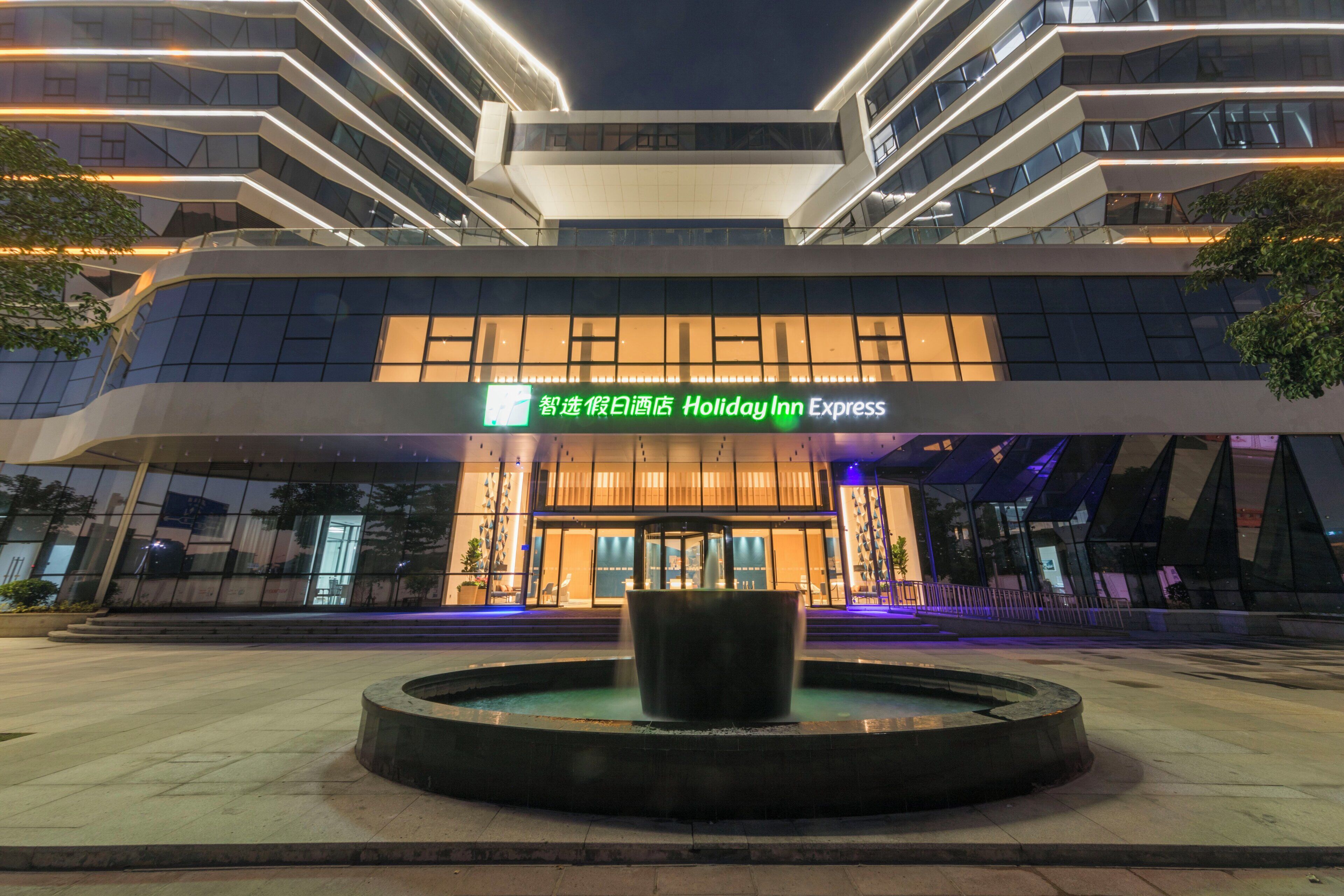 A modern hotel building with a prominent entrance and a central water feature.