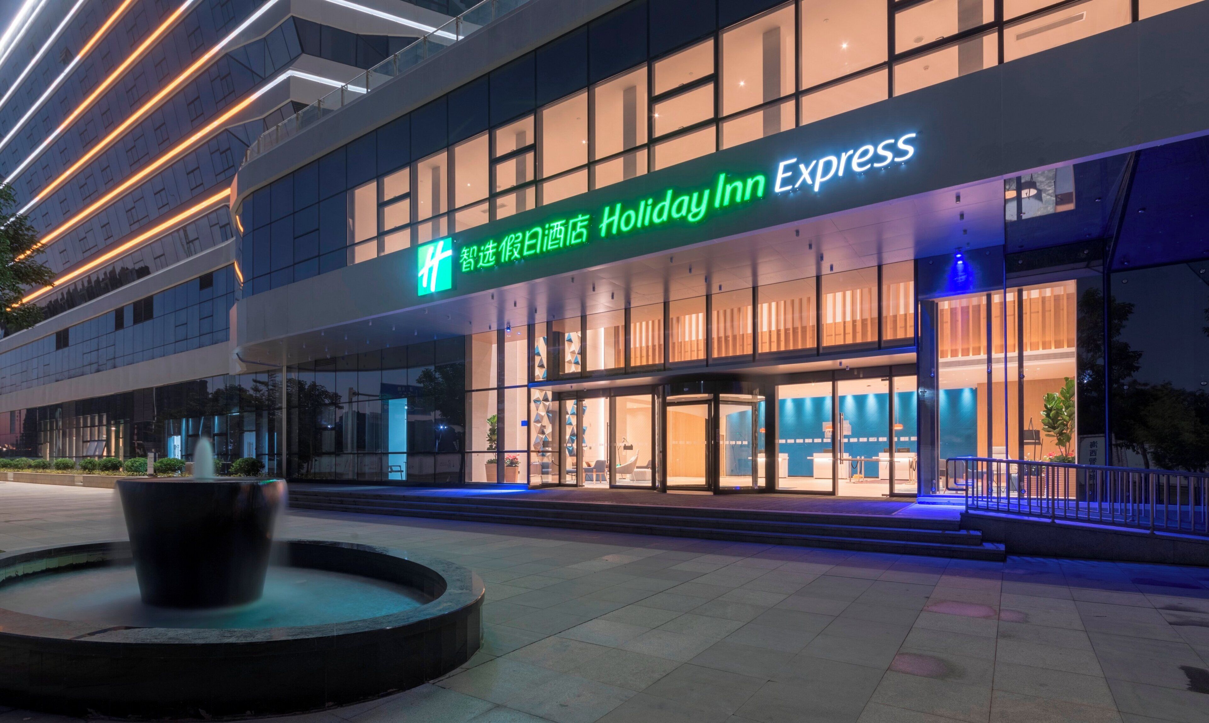 Um hotel Holiday Inn Express com fachada moderna, grandes janelas e entrada bem iluminada.