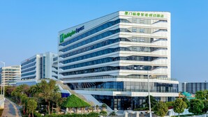 Un hotel moderno con un llamativo letrero de 'Holiday Inn Express', varios pisos y una escalera que conduce a la entrada.