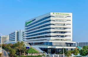 Un hotel moderno con un llamativo letrero de 'Holiday Inn Express', varios pisos y una escalera que conduce a la entrada.