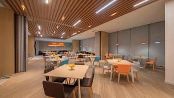 Un interior moderno con techos de listones de madera, varias mesas y sillas, y una paleta de colores neutros.