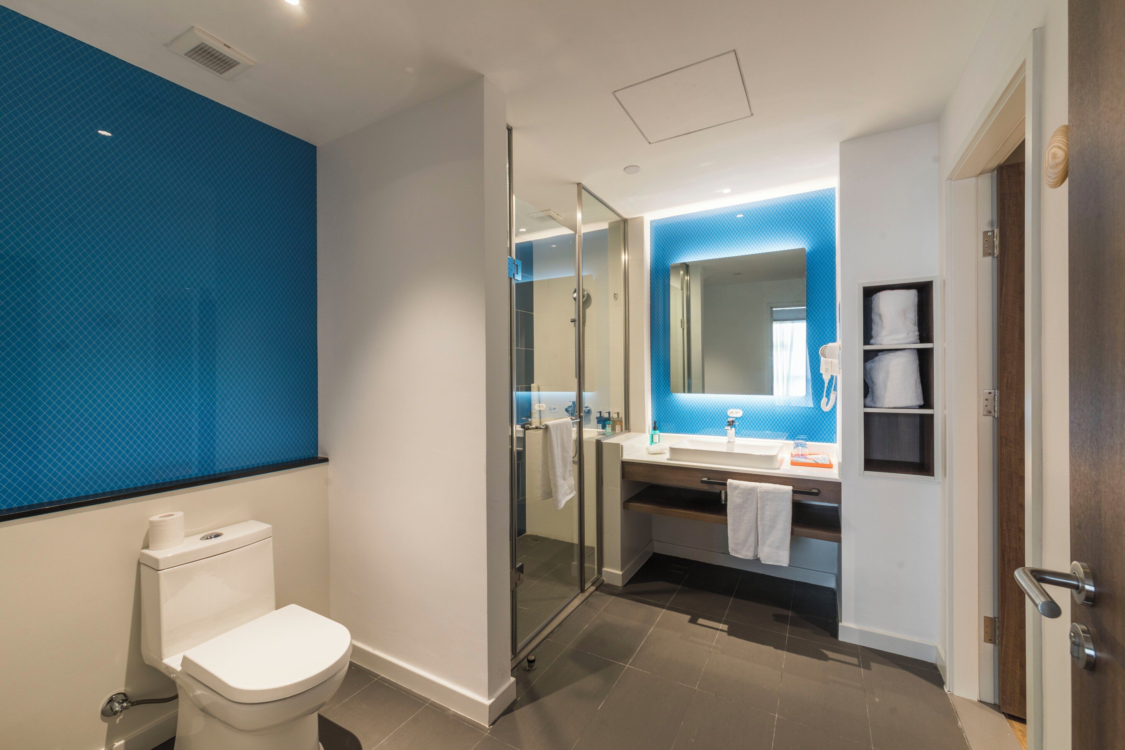 Een moderne badkamer met een douchecabine van glas, een wit toilet en een wastafel met spiegel.