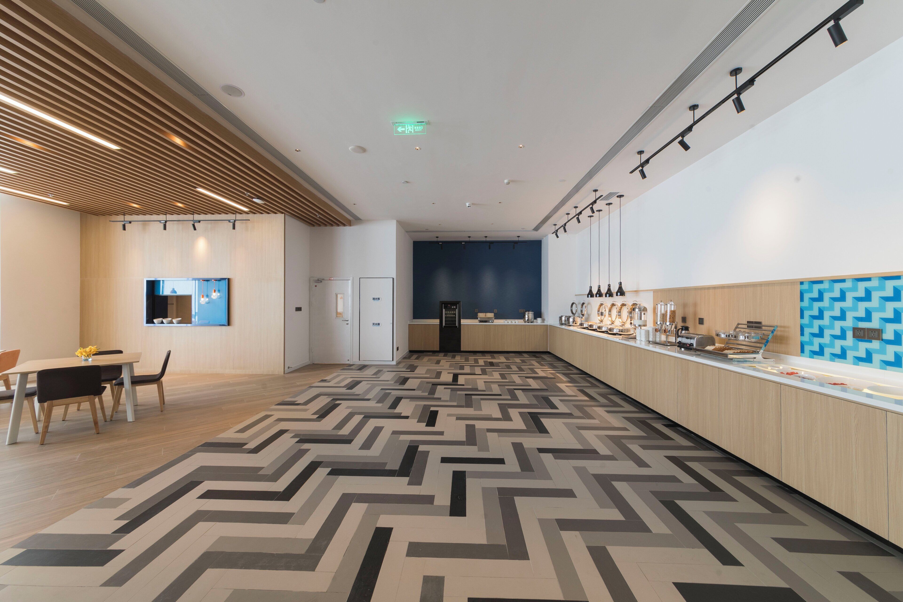 Un intérieur moderne avec un long comptoir, un espace salon et un sol à motifs.