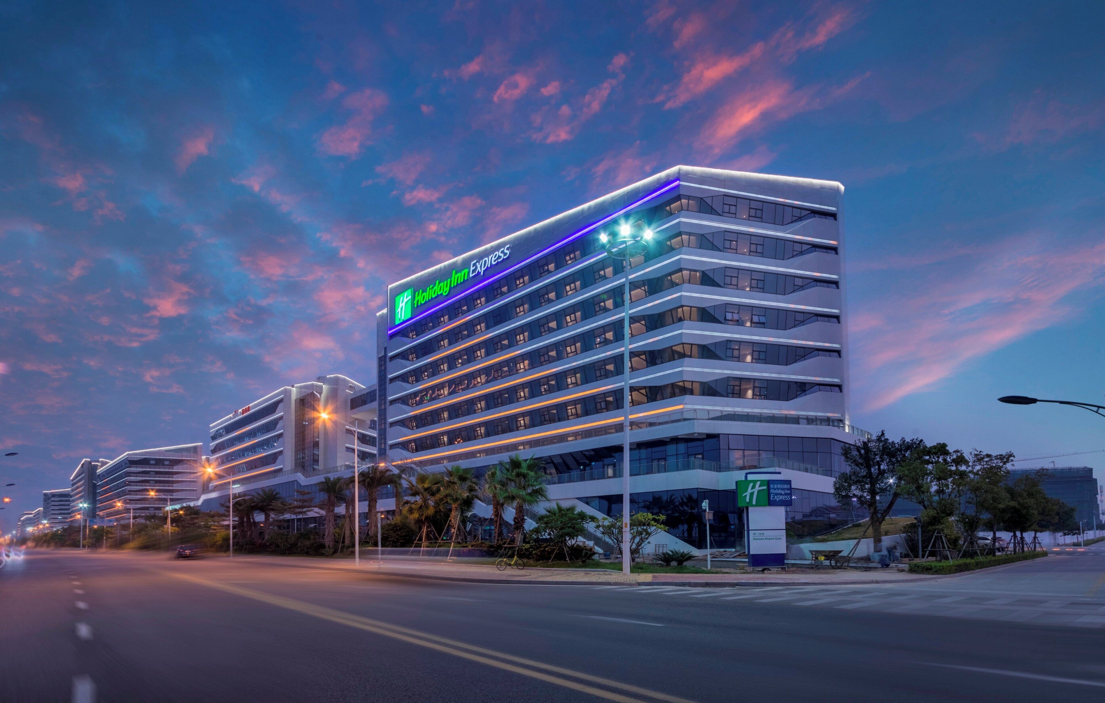 A multi-story Holiday Inn Express hotel with a modern design, featuring a prominent green and white logo.