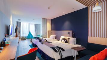 A modern hotel room with a large bed, a desk with a chair, a sofa, and a tent in the background.