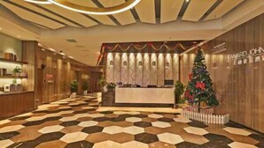 A hotel lobby with a reception desk, a Christmas tree, and a check-in counter. - Howard Johnson Life Changrong (Qinzhou)