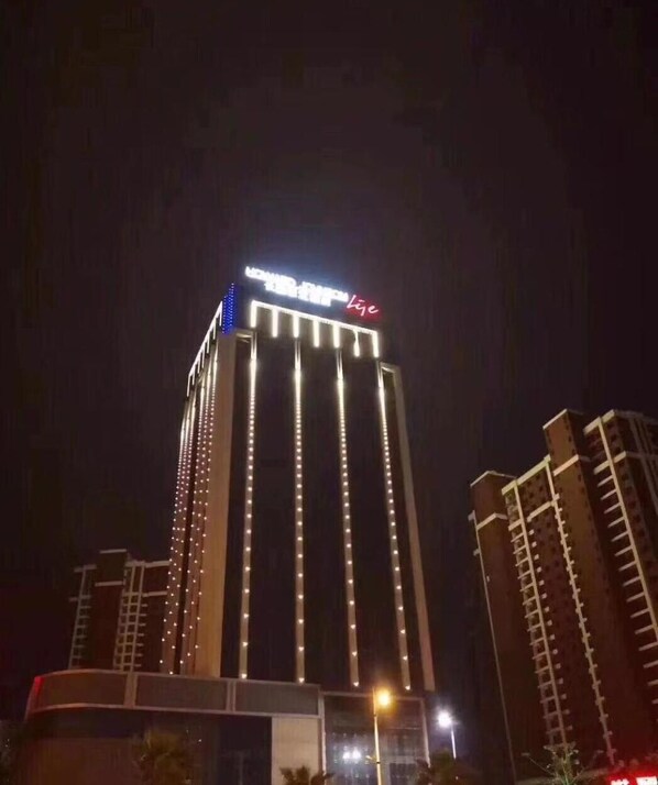 Un edificio alto con tiras de luz verticales y un letrero en la parte superior.