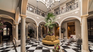 A grand lobby with a checkered floor, high ceilings, and classical columns.