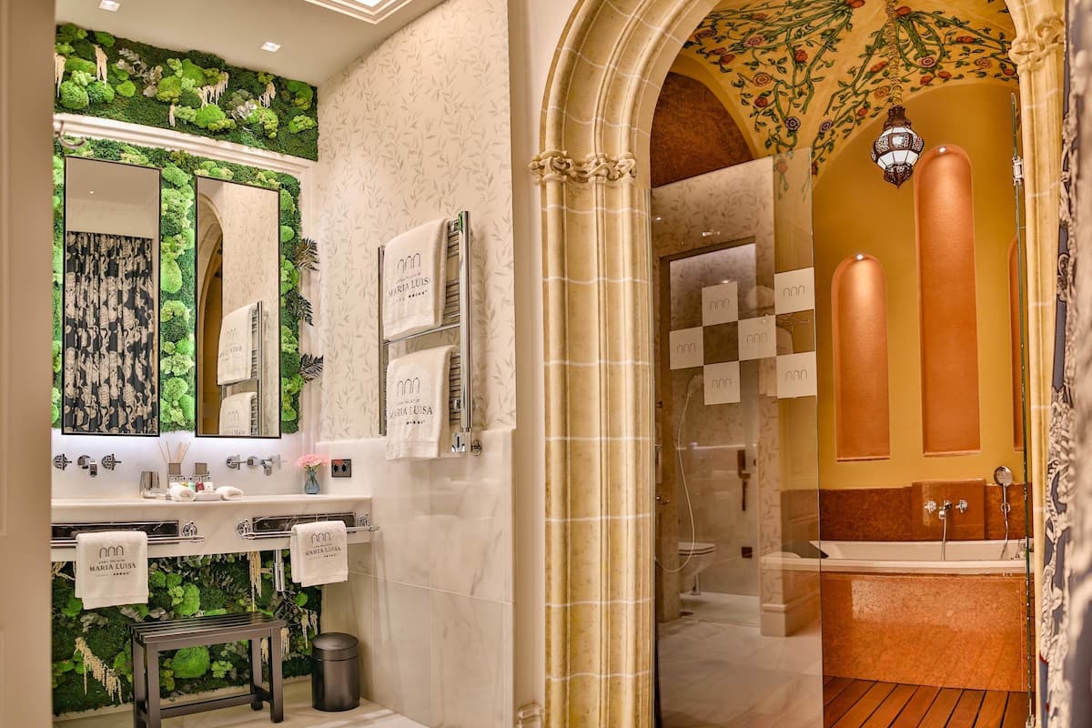 A modern bathroom with a green wall, a large mirror, a vanity with a sink, and a shower area.