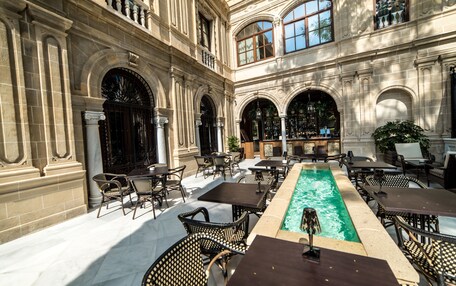 An outdoor patio with a pool, tables, and chairs.