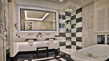 Un baño moderno con un espejo grande, una bañera y un tocador con dos lavamanos.