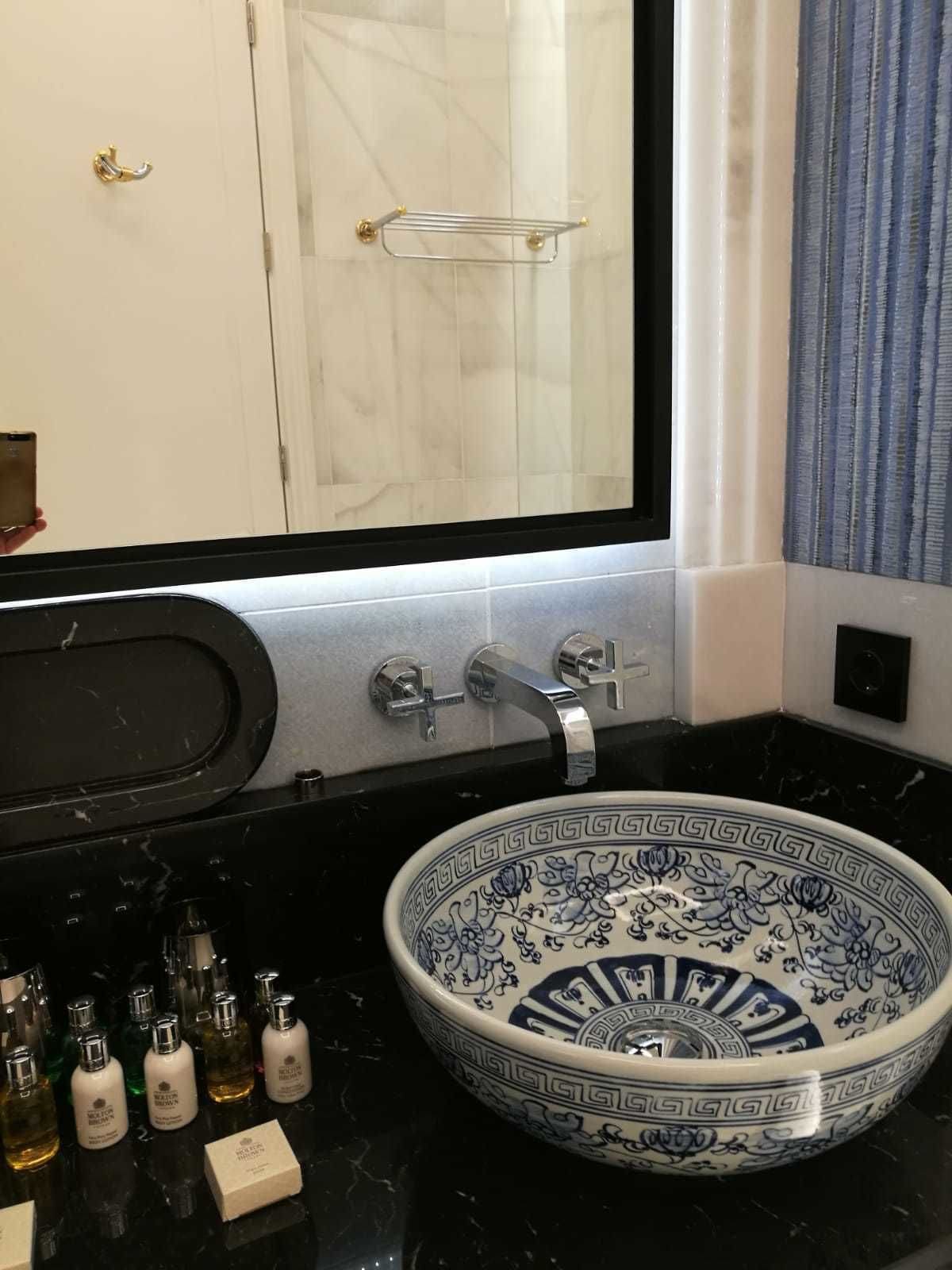A bathroom with a large sink, a mirror, and a towel rack.