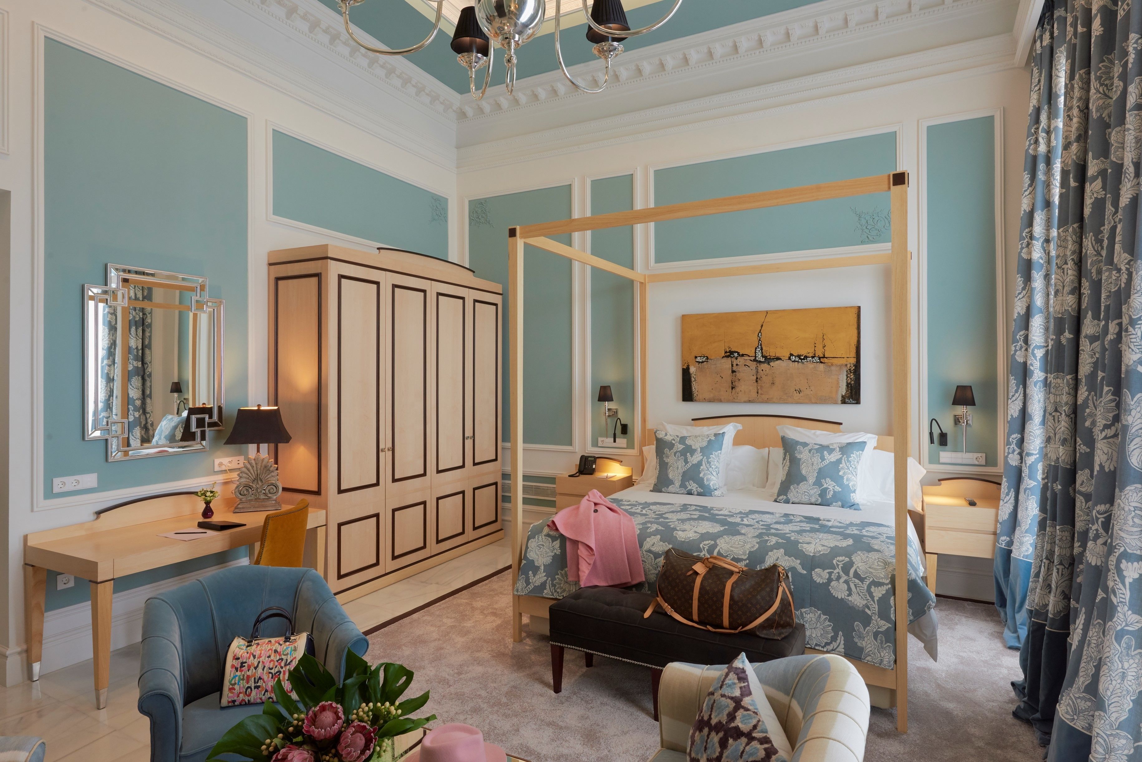 A bedroom with a four-poster bed, a desk, a chair, and a wardrobe.
