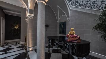 Um hall imponente com piso quadriculado, uma estátua e um piano.
