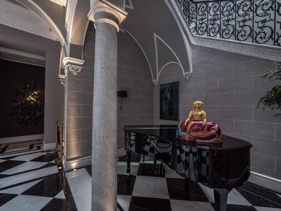 Um hall imponente com piso quadriculado, uma estátua e um piano.