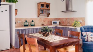 A kitchen with a wooden table, chairs, a microwave, and a cabinet above the counter. - La Casa de Bobadilla Alojamiento Rural (Alcaudete)