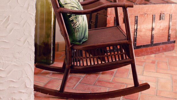 A rocking chair with a cushion, a wooden cabinet, and a tiled floor. - La Casa de Bobadilla Alojamiento Rural (Alcaudete)