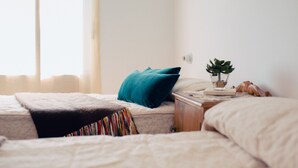 A bedroom with two beds, a bedside table with a plant, and a window with curtains. - La Casa de Bobadilla Alojamiento Rural (Alcaudete)