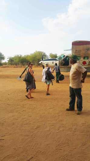 A group of people walking towards a small aircraft in a desert setting.