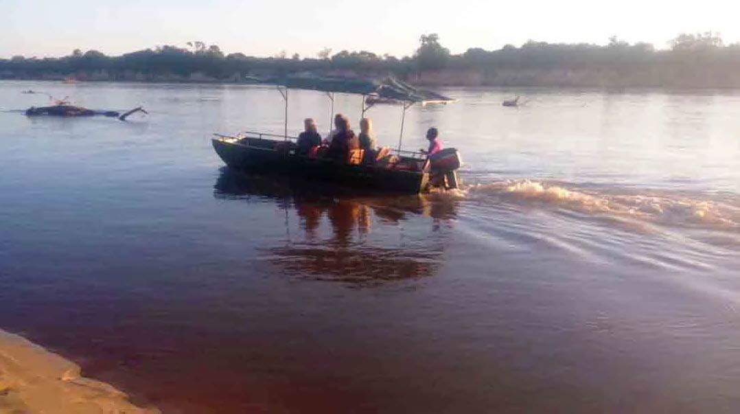 Un barco con pasajeros en un río tranquilo.