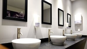 Ein modernes Badezimmer mit drei Waschbecken, jeweils mit einem separaten Spiegel und Wasserhahn.