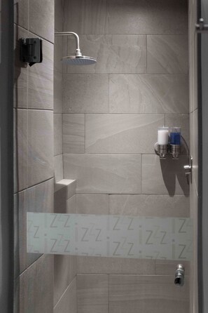 A shower with a handheld showerhead, a soap dispenser, and a towel rack. - izZzleep Aeropuerto Terminal 2 (Mexico City)