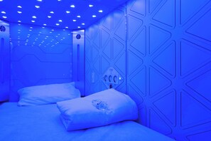 A room with a geometric wall design, a bed with white bedding, and a control panel on the wall. - izZzleep Aeropuerto Terminal 2 (Mexico City)