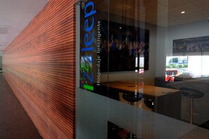 Un interior moderno de hotel con un muro de paneles de madera, una zona de bar y un conjunto de asientos.