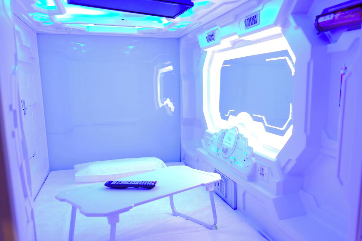 Een kamer met een bed, een nachtkastje en een bedieningspaneel aan de muur.